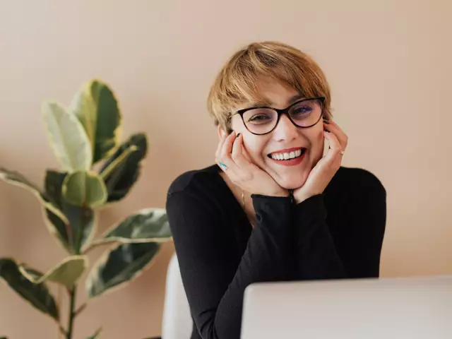 A smiling woman sitting at her laptop at home