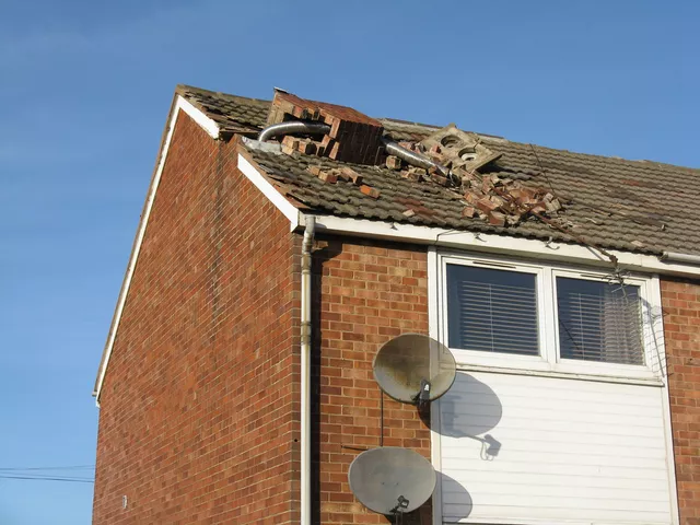 A house roof in the UK with a chimney stack blown down across the tiles in a storm
